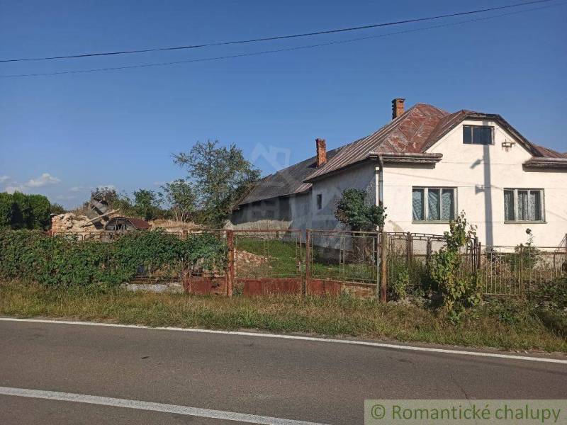 A family house by the road with fencing, an old fence, and a neglected garden.