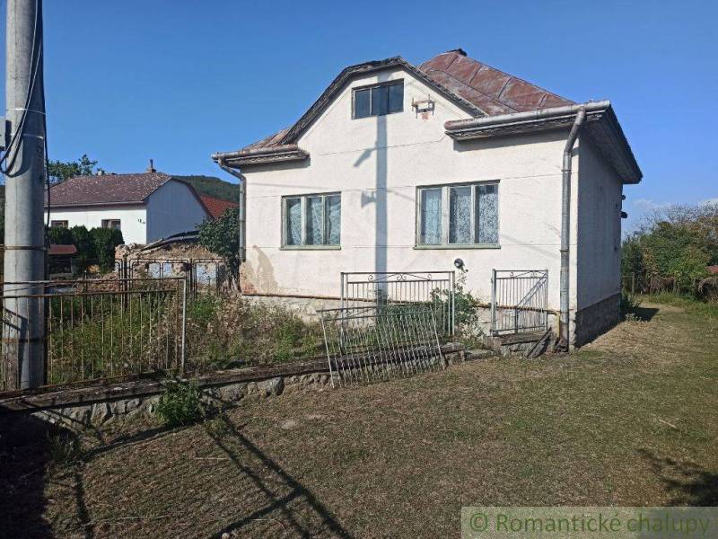 Family house with a white facade, sloped roof, garden, metal fence, peaceful location.