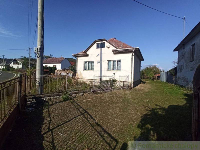 A family house with a lawn, a fence, and an electric pole in the countryside.