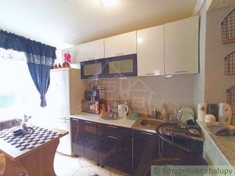 A kitchen in a family house with a comfortable corner window and dark kitchen furniture.