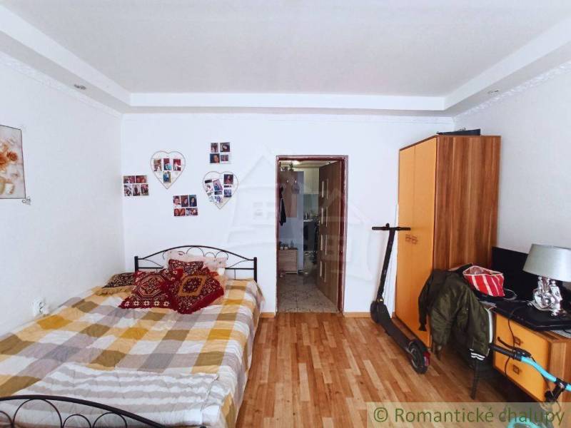 A bedroom in a family house with wooden flooring, decorative wallpaper, and storage space.