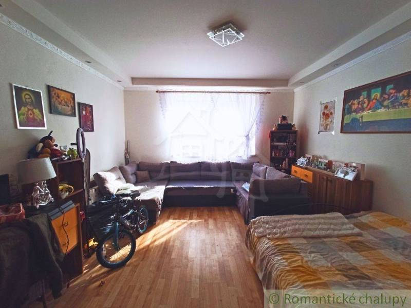 A living room with a sofa and a bicycle in a family house, located near the window.