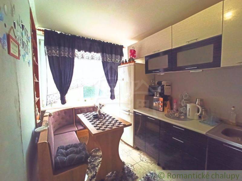 A kitchen in a family house with a dining table, bench, coffee maker, elegant curtains, and decorations.