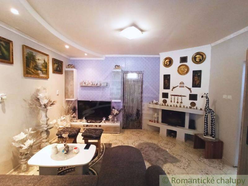 Living room in a family house with a fireplace, couch, decorations, and a television on a blue wall.