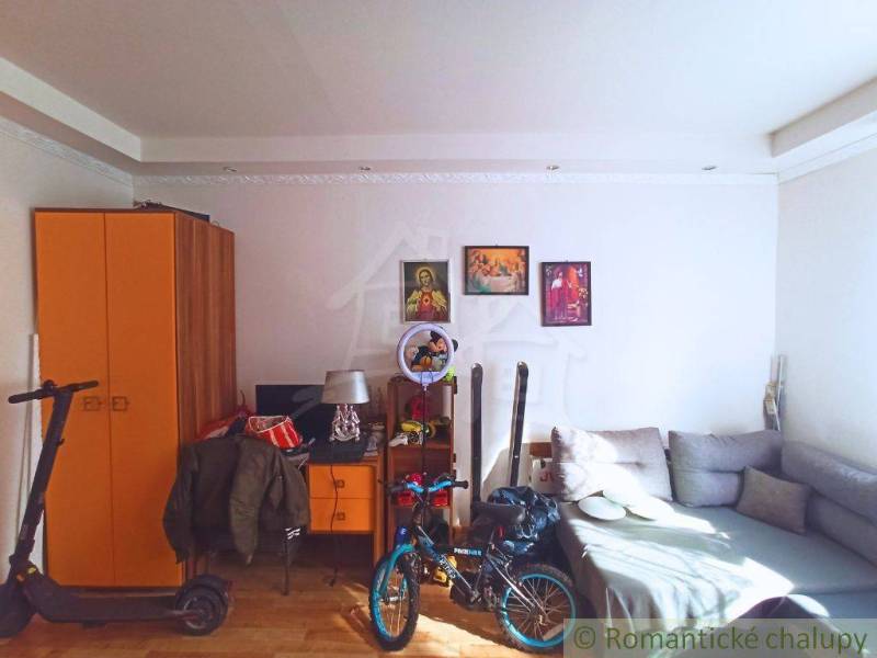 A room in a family house with an orange wardrobe, a couch, and a bicycle, ideal for a family.