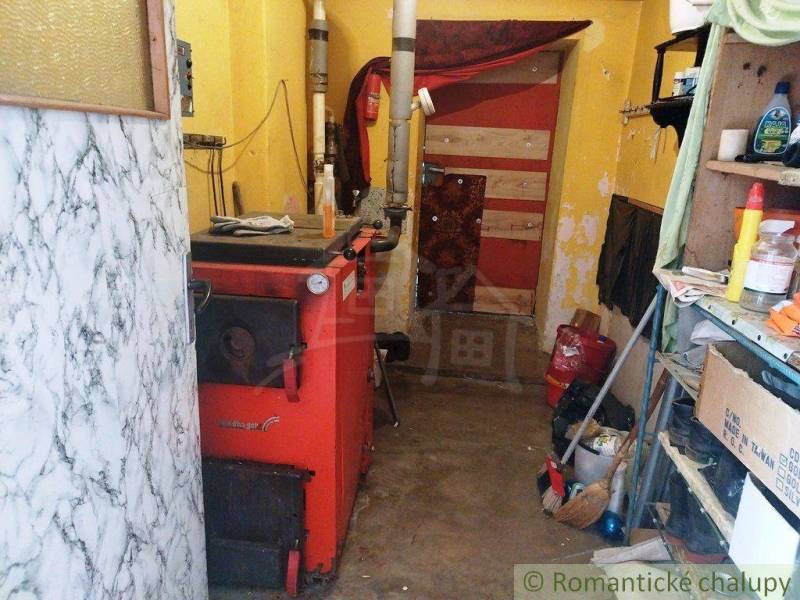 Boiler in the family house boiler room, wood, tools, storage shelves, and basket.