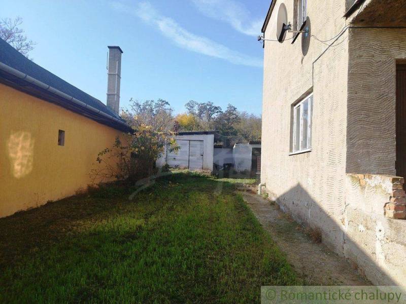A family house with a garden between buildings near the family house, greenery can be seen in the background.
