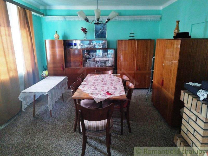 A dining room in a family house with wooden furniture, a table, and a blue wall.