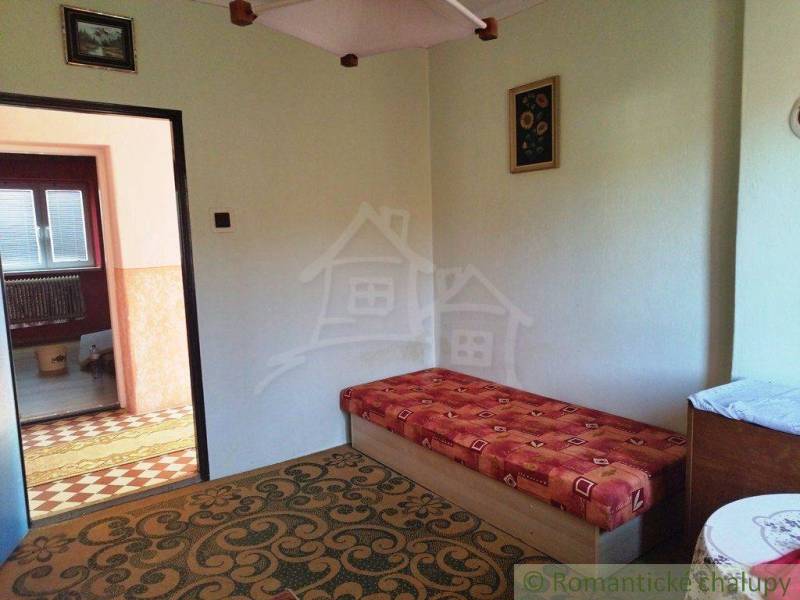 A room with older furniture, carpet, wallpaper, a painting, and a view into another room.