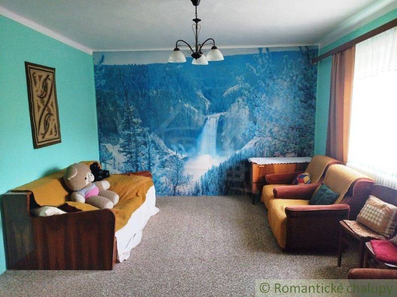 Living room with mountain wallpaper, sofa, armchairs, teddy bear. Interior of a family house.