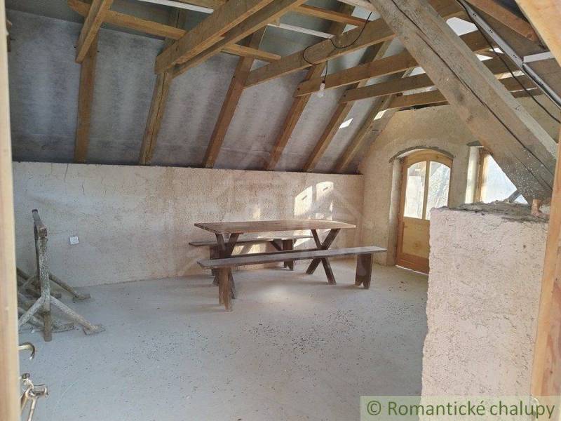 Attic room with a wooden table, benches, wooden beams, and doors, ideal for a cabin.