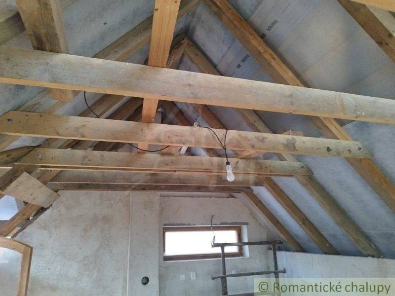 The roof of the cottage with wooden beams, exposed light bulb, rustic style.