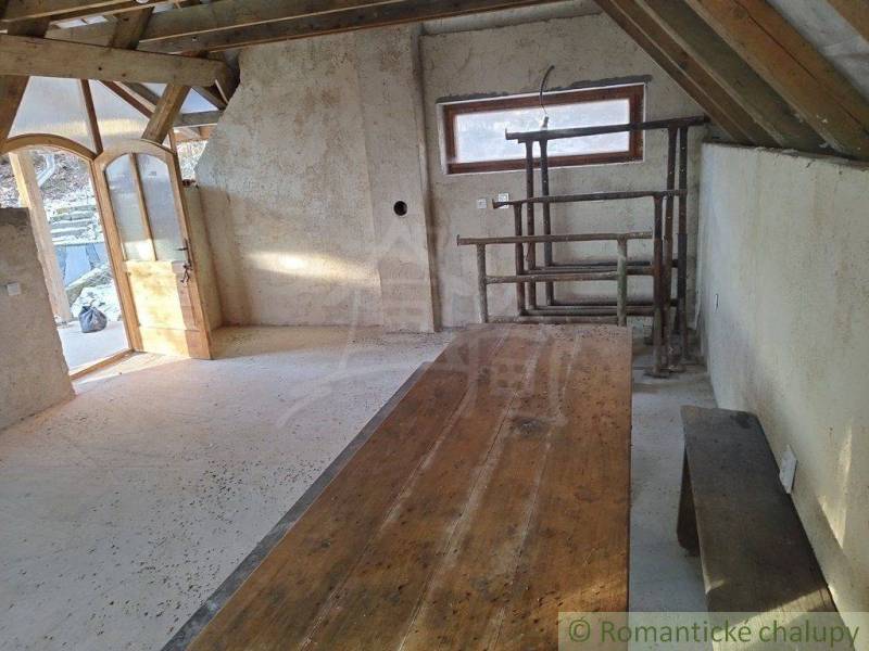 A rustic cottage with a wooden table, bench, and arched door creates a cozy atmosphere.