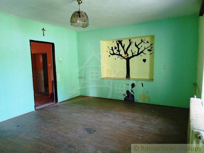 A room with a wooden floor, a painting of a tree on the wall, and lighting, ideal for a cabin.