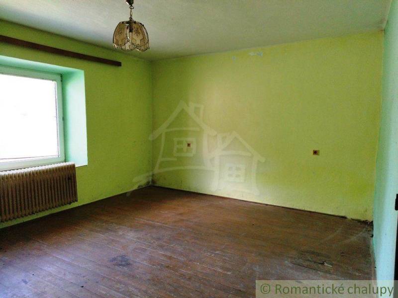 A room with a wooden floor, light yellow walls, and a simple light fixture on top. Cabin.