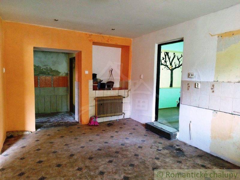 The interior of the cabin with tiling, protruding heating, and a visible transition to another room.