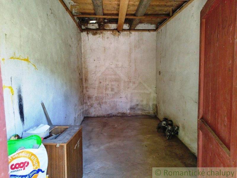 An older garage room with a wooden ceiling and simple walls in a cottage.