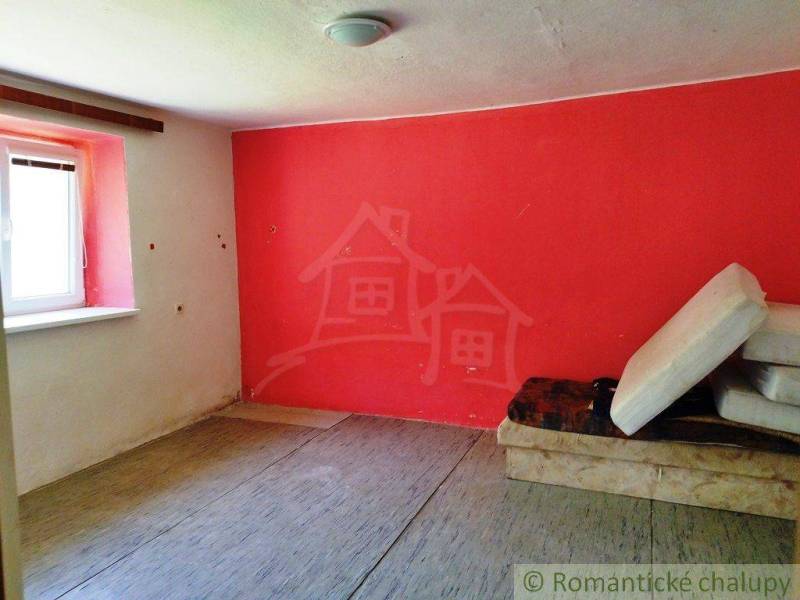 A room in a cottage with a striking red paint and a simple interior.