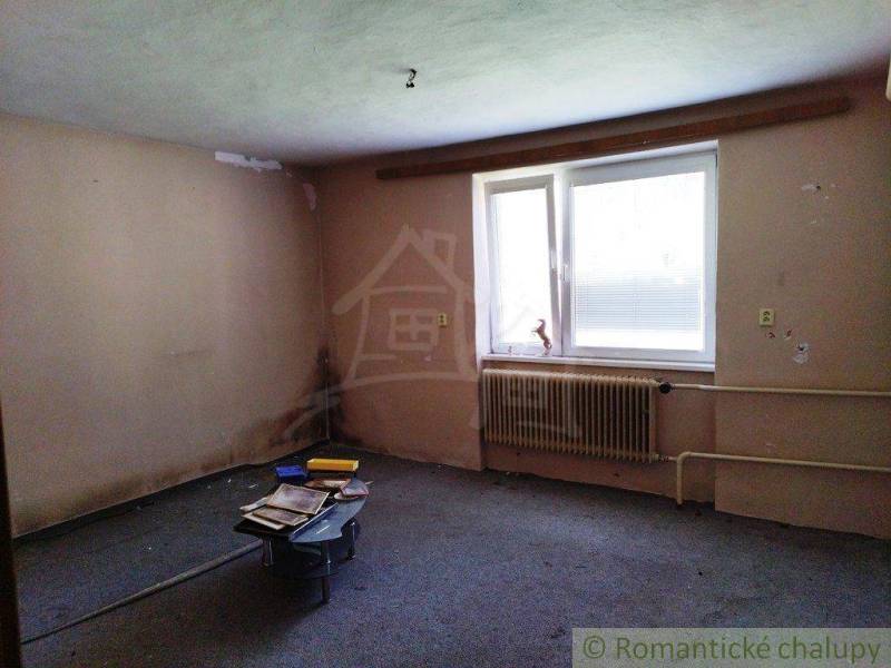 A room with bare walls, a table, and window blinds, suitable for renovating a cottage.