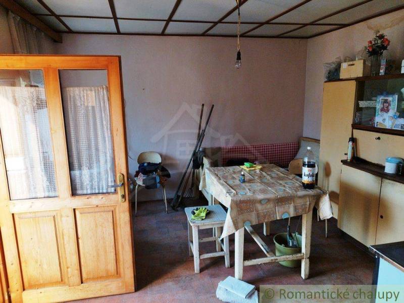 Dining room in a family house with wooden doors, a sofa, and a table with a tablecloth.