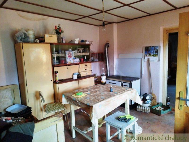 A kitchen in a family house with wooden furniture, a table, and a simple stove.