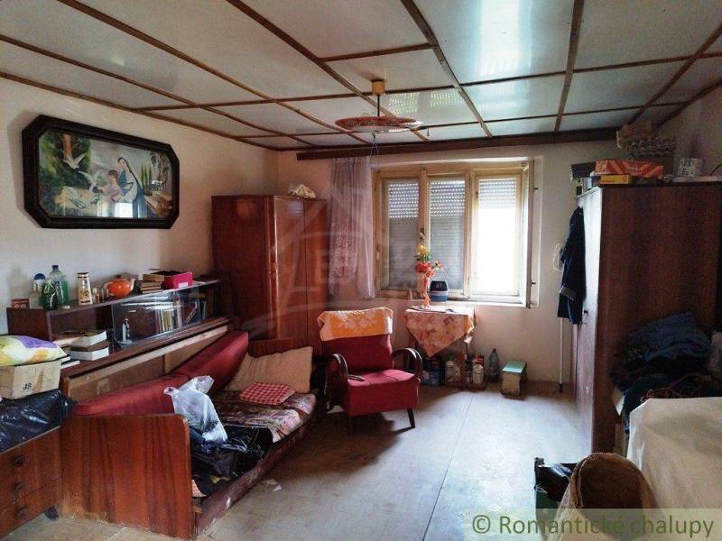 A room in a family house with furniture, decorations, and a large window offers comfort.