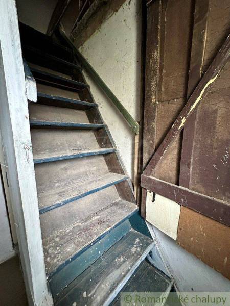 Narrow wooden stairs in an old family house with faded walls.