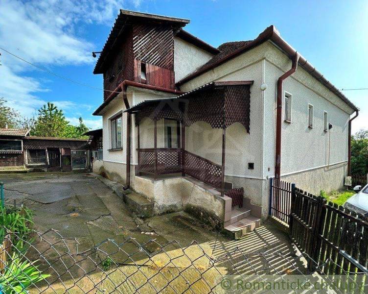 A family house with a spacious yard and a wooden arcade, ideal for living.