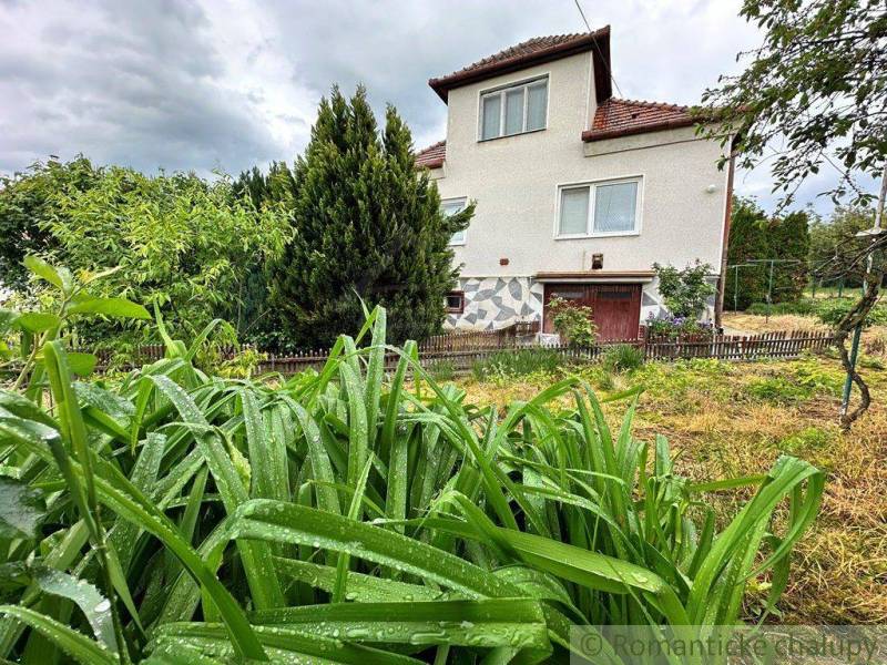 A family house among greenery and raindrops, fencing in the garden.