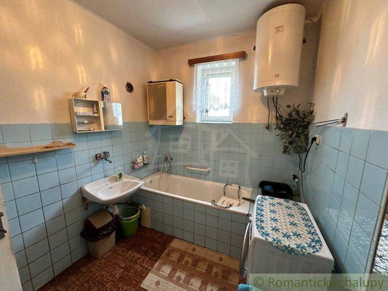 Bathroom in a family house with a bathtub, sink, and washing machine, decorated with blue tiles.