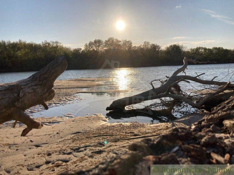 A river scene with a sandy shore, the reflection of the sun creates a serene image of the landscape.