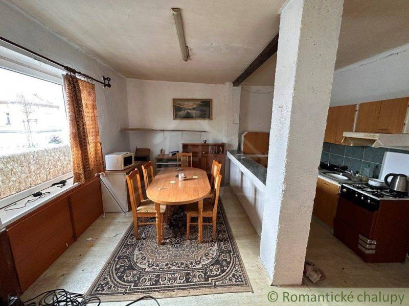 A kitchen in a family house with old furniture, a dining table, and appliances.