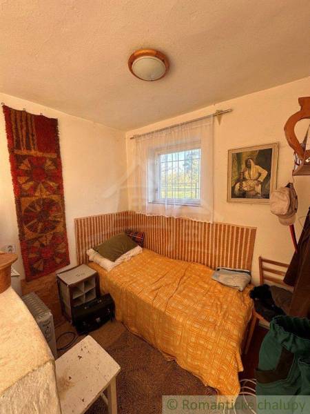 Small room, bed with an orange throw, window, painting, cabin decoration.