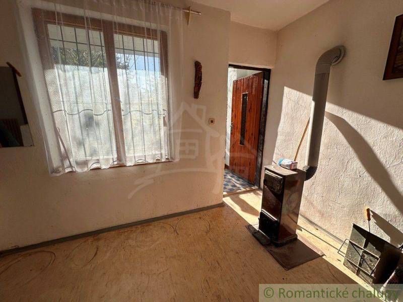 In the picture, there is a room and a cottage with a stove and a window.