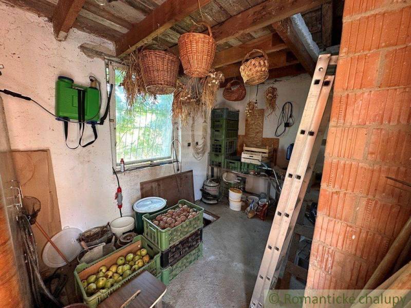 The picture shows a cozy cabin with a wooden ceiling, baskets, and stored fruit.
