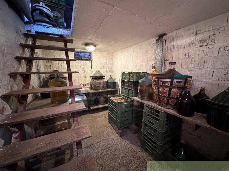 Cellar with wooden stairs, demijohns, and crates of wine for storage in the cottage.