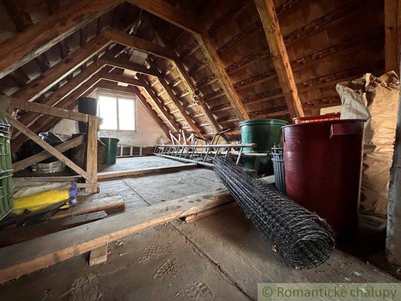Attic with storage items, ladder, and window, suitable for a cottage or cabin.