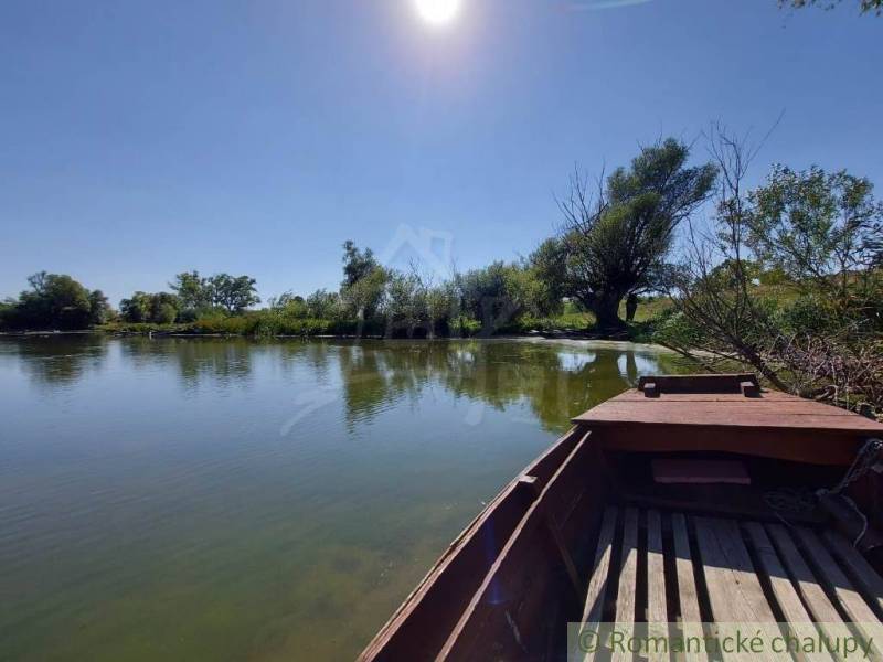A peaceful river with a boat surrounded by trees and a blue sky, ideal for plots - housing.