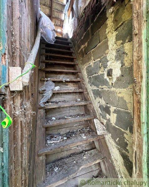 Old wooden stairs lead to the attic, surrounded by the shabby walls of the old house and cottage.
