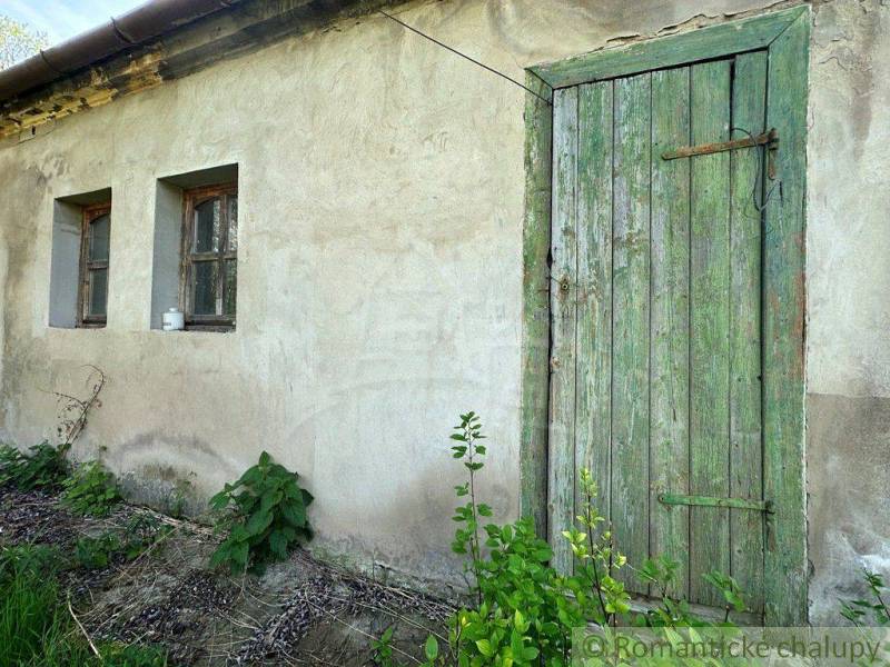 Green wooden door and plastered wall of a country cottage with old windows.