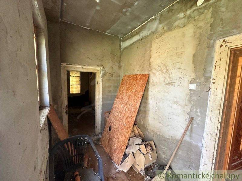 An unrenovated room in a cottage with a chair and building materials.