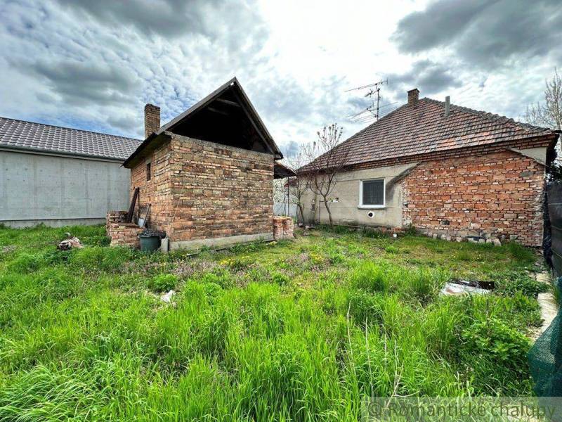 The image shows brick buildings on a plot with tall grass. Family house.