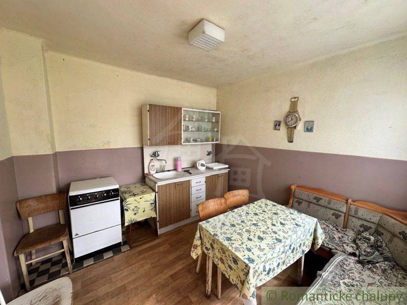 A kitchen unit and furniture with floral tablecloths in an older family house.