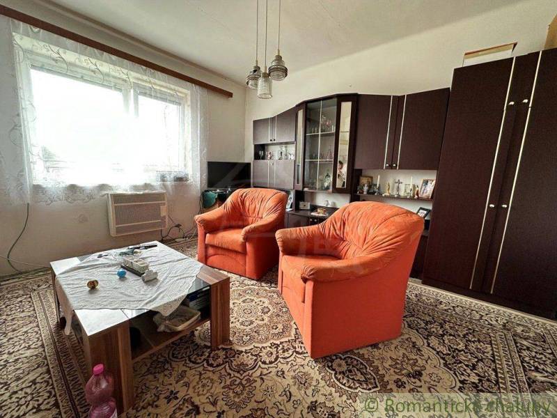 Living room with orange armchairs and a carpet, family house, older furniture.