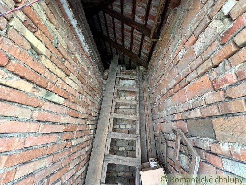 The attic space of a family house made of old bricks, with a wooden ladder leading to the loft.