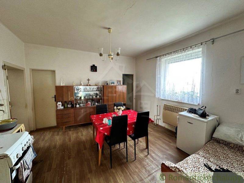 Dining room with a table and chairs, a cabinet, and a family house with a window and a stove.