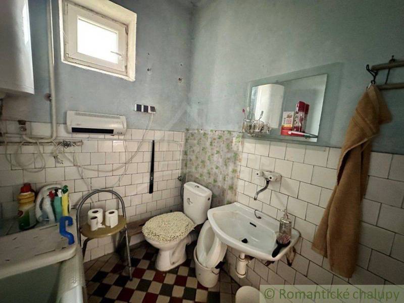 A bathroom with older fixtures, a toilet, and a sink in a family house.