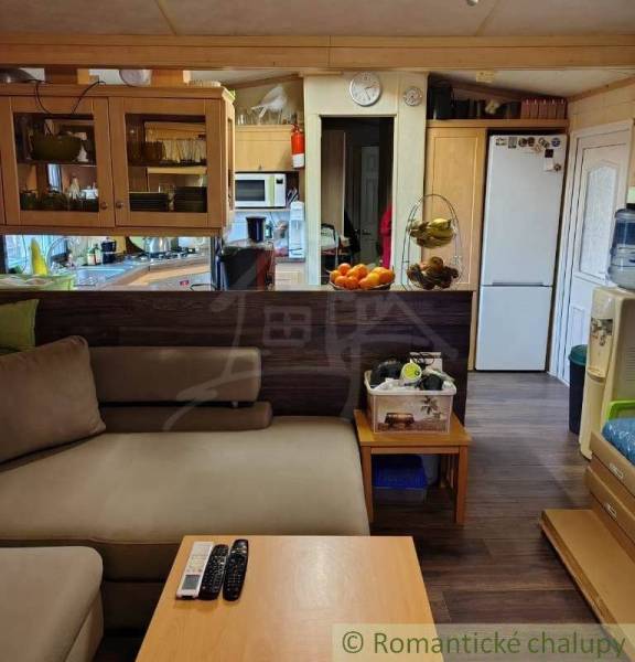 Interior with a kitchen and living room in a family house. Comfortable sofa, refrigerator, dining table.
