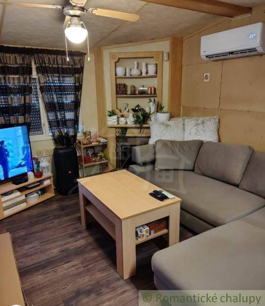 Living room in a family house with a corner sofa, table, and air conditioning vent.