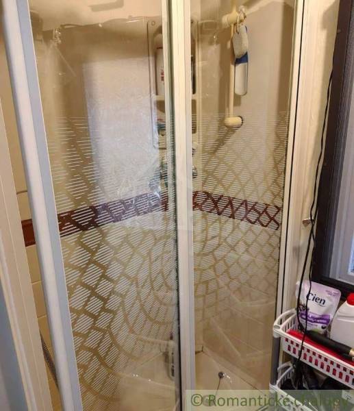 Shower enclosure in the bathroom of a family house, with glass doors and shower accessories.